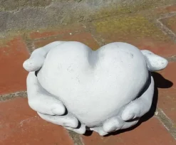 Hænder holder/giver hjerte i hvid beton