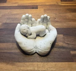 Hænder med baby i hvid cement